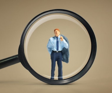 Das Bild zeigt eine Lupe, die einen Interim Manager vergrössert.