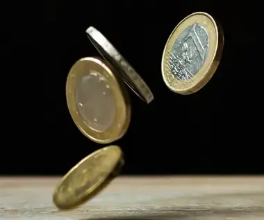 Mit Interim Management finanzielle Herausforderungen lösen: Das Bild zeigt Geldmünzen, die auf einen Tisch fallen.