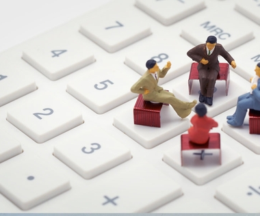 Digitales Reporting: Das Bild zeigt vier Figuren, die auf einer Tastatur sitzen.