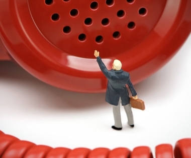 Feedback-Kultur für agile Organisationsentwicklung: Das Bild zeigt eine Figur vor einem roten Telefonhörer.