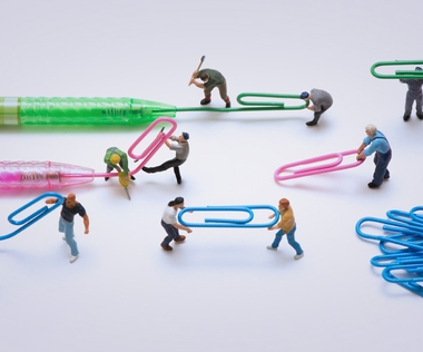 Markenmanagement: Das Bild zeigt Figuren, die Kugelschreiberminen in Büroklammern transformieren.