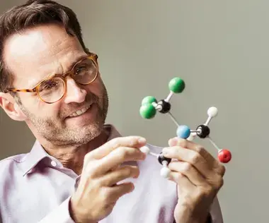 Mit Interim Management Business-Herausforderungen meistern: Das Bild zeigt einen Mann mit einem Molekül-Modell in den Händen.