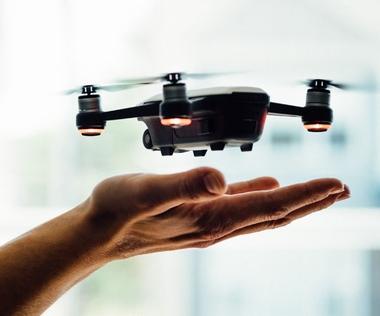 Interim Management Operations: Das Bild zeigt eine kleine Drohne, die knapp über einer ausgestreckten Hand, bereit zum Start oder zur Landung, schwebt.