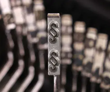 Interim Management Legal: Das Bild zeigt den Tastenhebel einer Schreibmaschine mit dem Paragraphenzeichen.