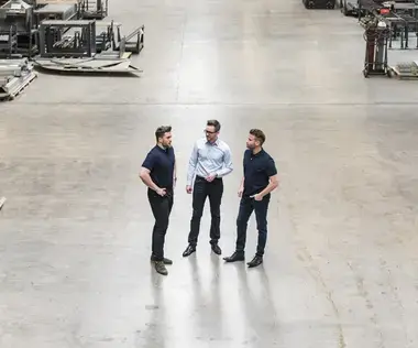 Interim Management Opertaions: Das Bild zeigt drei Männer in einer Produktionshalle aus der Vogelperspektive. 
