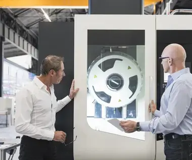 Interim Management Operations: Das Bild zeigt zwei Operations Manager vor einer Produktionsmaschine. 