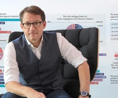 Tilo Ferrari auf einem Sessel. Im Hintergrund Ergebnisse des di-Trendbarometers an eine Wand projiziert.