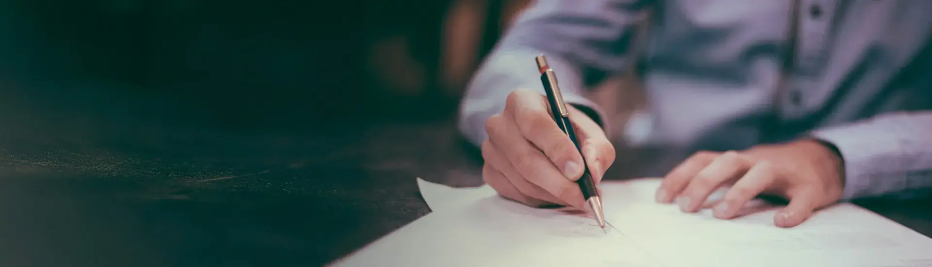 Interim Buchhalter: Das Bild zeigt einen Interim Buchhalter, der auf ein Blatt Papier schreibt.