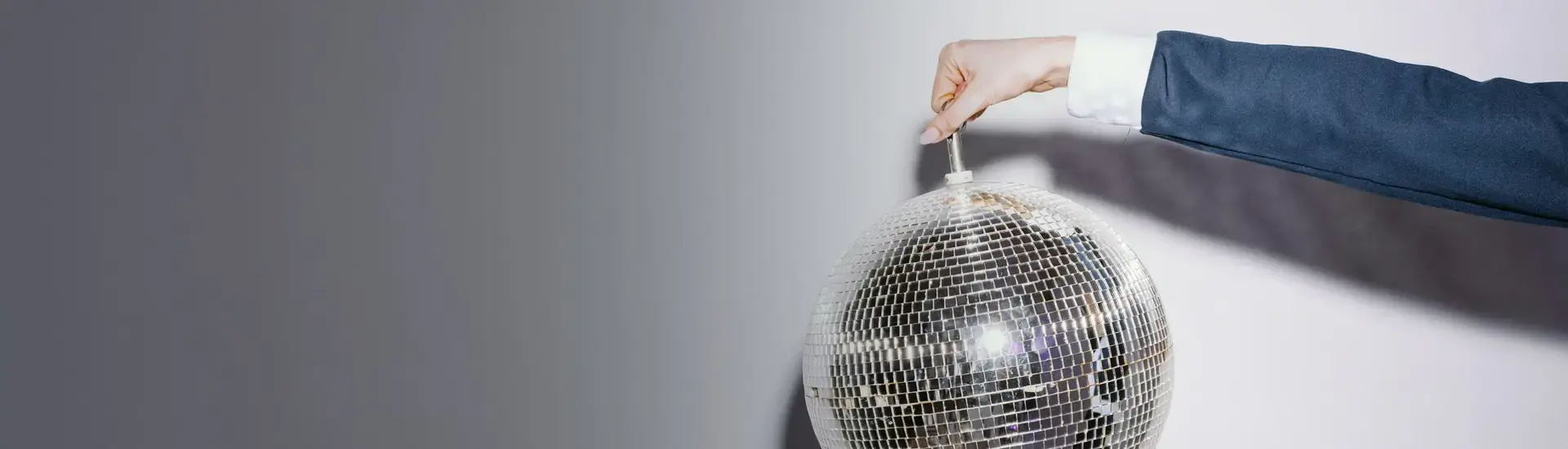 Interim Management Marketing: Das Bild zeigt einn Frauenarm. Die Frau hebt eine silberne Diskokugel in die Luft.