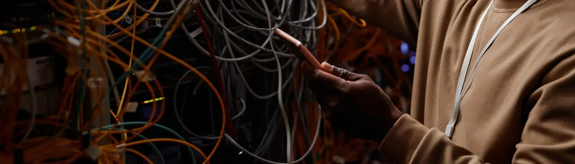 Interim IT Security Management: Das Bild zeigt einen jungen Mann in einem Serverraum mit Unmengen an Kabeln.