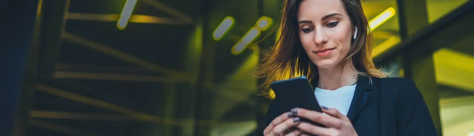 Das Bild zeigt eine junge Frau, die auf ihr Smartphone schaut.