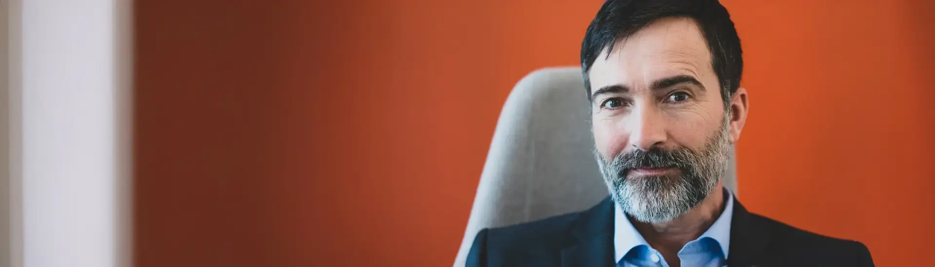 Interim CEO: Das Bild zeigt einen Interim CEO vor einer roten Wand.