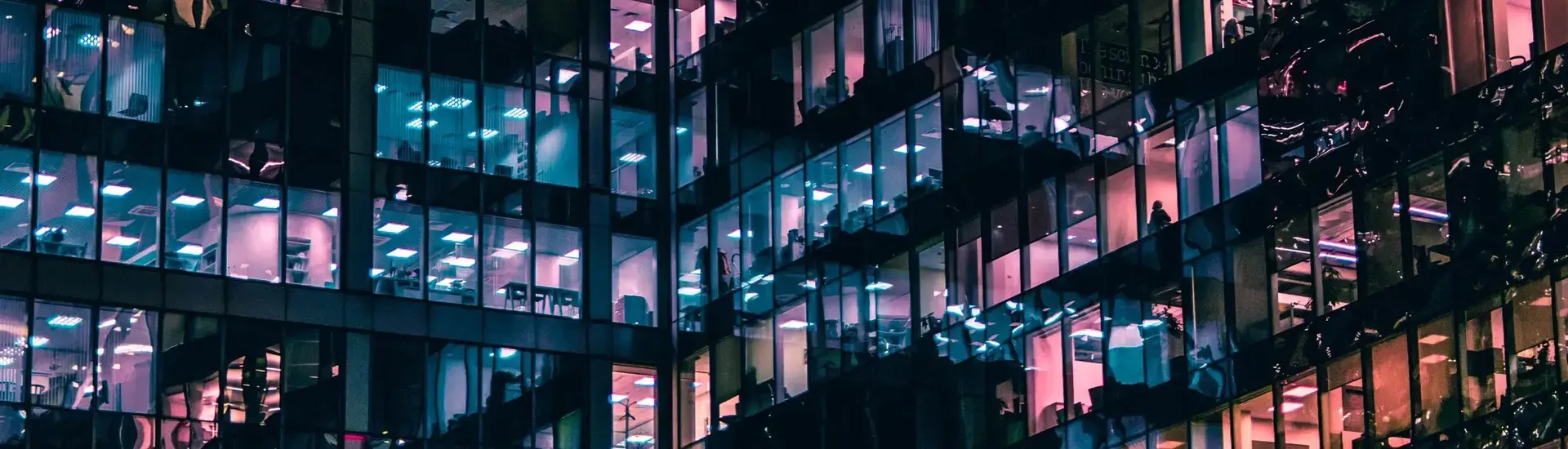 Interim Management HR: Das Bild zeigt ein Bürogebäude mit farbig beleuchteten Fenstern.