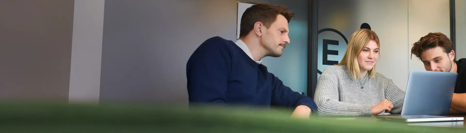 Interim Management Interne Kommunikation: Das Bild zeigt drei Kommunikationsmanager, arbeitend an einem Laptop.