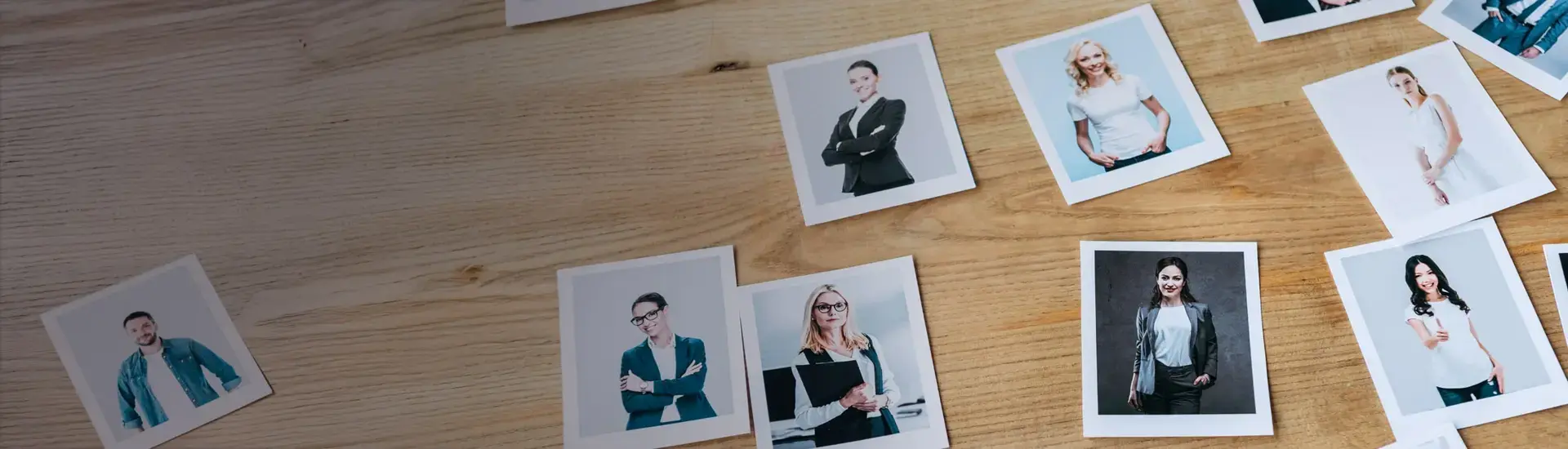 Interim Management Personalentwicklung und Personaltraining: Das Bild zeigt Polaroid-Bilder mit Menschen auf einem Holztisch.