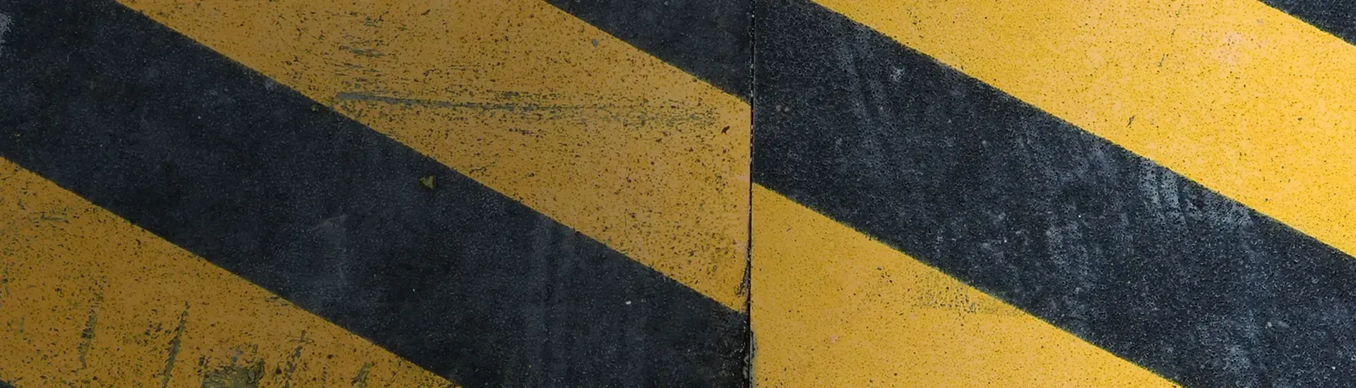 Interim Risikomanagement: Das Bild zeigt ein schwarz-gelbes Warnstreifenmuster.