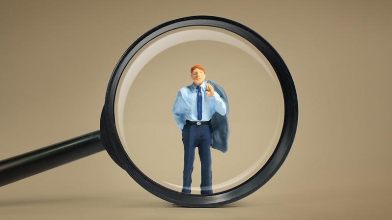 Das Bild zeigt eine Lupe, die einen Interim Manager vergrössert.