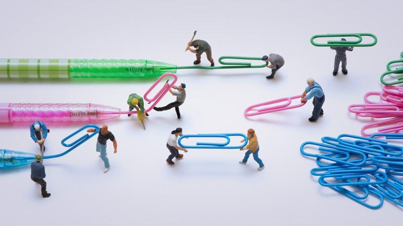 Markenmanagement: Das Bild zeigt Figuren, die Kugelschreiberminen in Büroklammern transformieren.