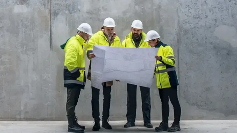 Mit Interim Management Business-Herausforderungen lösen: Das Bild zeigt Arbeiter, die einen Bauplan studieren.