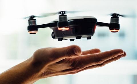 Interim Management Operations: Das Bild zeigt eine kleine Drohne, die knapp über einer ausgestreckten Hand, bereit zum Start oder zur Landung, schwebt.