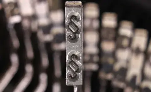 Interim Management Legal: Das Bild zeigt den Tastenhebel einer Schreibmaschine mit dem Paragraphenzeichen.