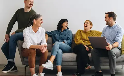 Mit Interim Management HR-Herausforderungen bewältigen: Das Bild zeigt Mitarbeitende auf einem Sofa.