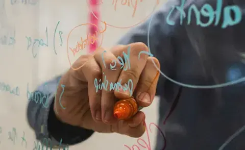 Interim Management: Das Bild zeigt, wie ein transparentes Whiteboard beschriftet wird. 