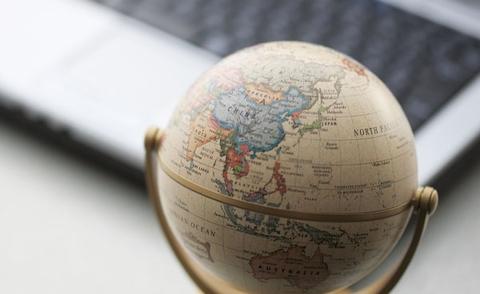 Interim Management: Das Bild zeigt einen Schreibtisch mit einem Laptop und einem kleinen Globus. 